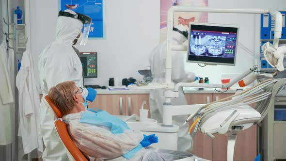 Stomatologist in Protective Suit Explaining Dental Radiography