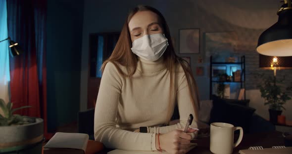 Young Student Wearing Medical Protective Mask Using Laptop with Video Conference Call