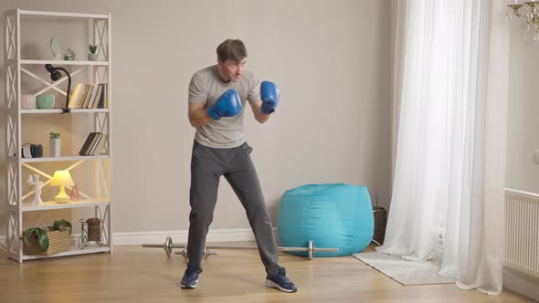Wide Shot of Confident Handsome Male Boxer in Boxing Gloves Fighting Shadow