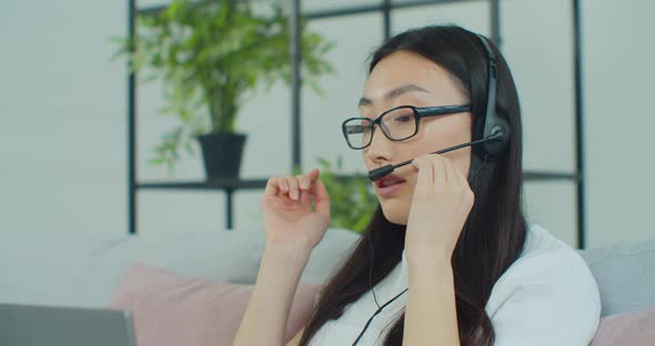 Close Up Beautiful Young Asian Woman Wear Headphone Communicating Video Conference Call Speak Home