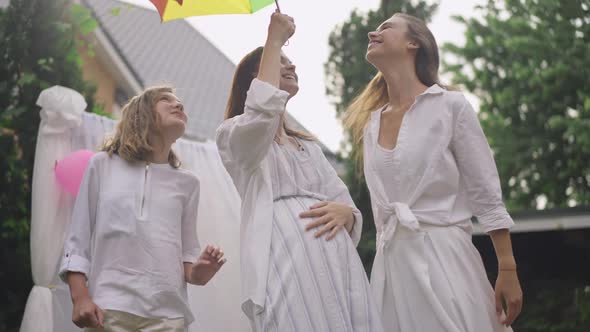 Joyful Carefree Pregnant Woman and Girls Dancing in Slow Motion Admiring Colorful Umbrella on Sunny