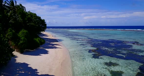 Wide aerial travel shot of a white sandy paradise beach and blue sea background in colourful 4K