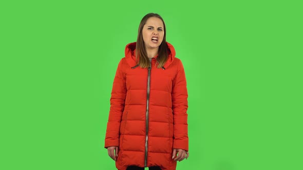 Lovely Girl in a Red Down Jacket Is Showing Disgust for Bad Smell or Taste. Green Screen