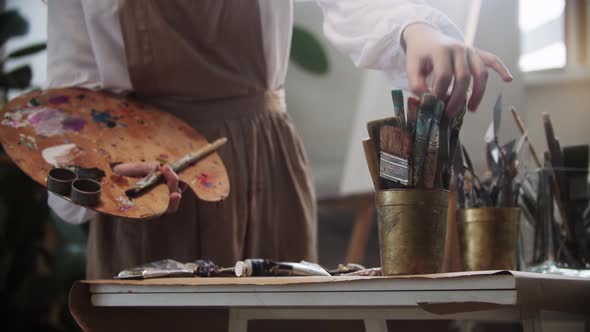 Young Woman Artist Choosing a Brush From the Table