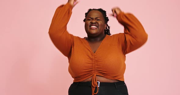 AfroAmerican Plump Woman Rejoices Raising Fists for Camera