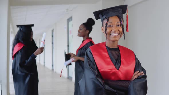 A Joyful Female Graduate with a Diploma in Hand Stands at the University Against the Background of