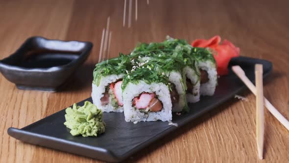 Sprinkle Sushi with Sesame Seeds on a Wooden Table in Restaurant