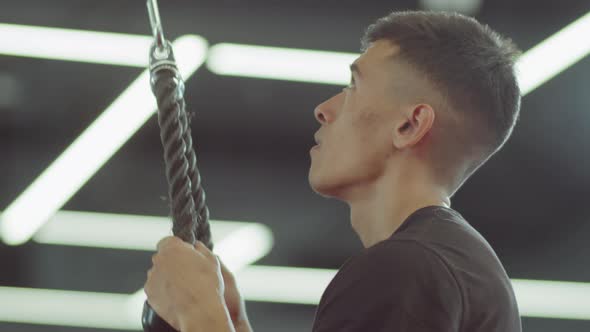 Man Doing Standing Pulldowns with Cable Machine in Gym