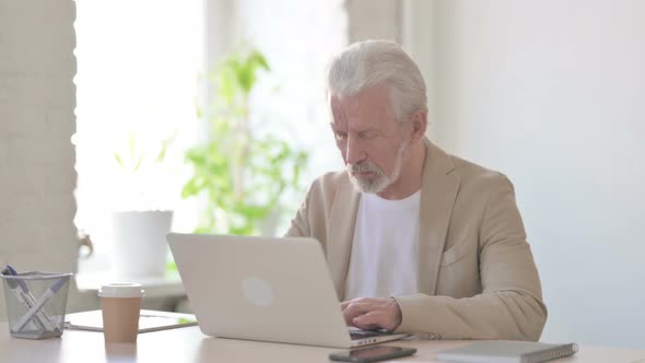 Busy Old Man Using Laptop in Office