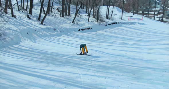 Male Athlete Puts on and Fastens a Snowboard, Prepares for Snowboarding. Winter Sport. Aerial View