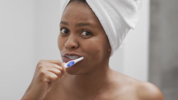 Happy african american woman brushing teeth in bathroom