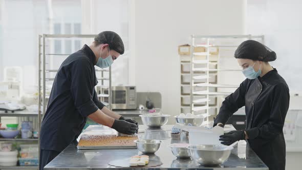 Side View of Two Concentrated Confectioners Working in Candy Store Kitchen in Slow Motion