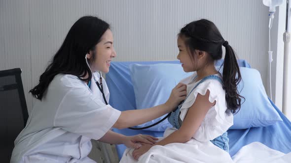 Asian doctor using stethoscope to diagnose female child