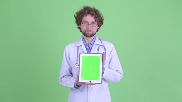 Stressed Young Bearded Man Doctor Showing Digital Tablet