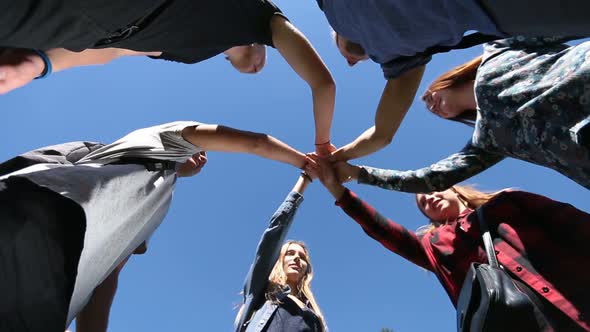 College Students Stacking Hands on Park Lawn