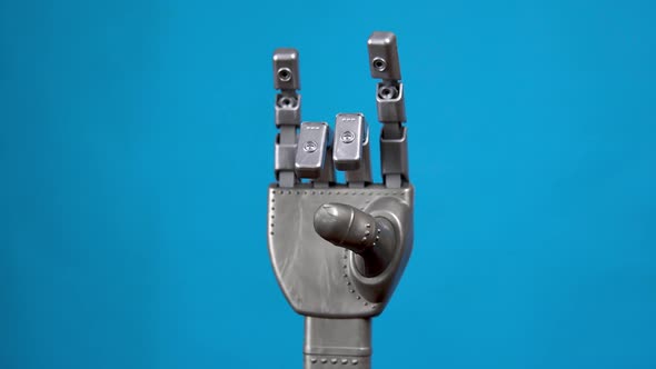 A Mechanical Hand Flexes Its Fingers and Shows a Rock Sign. Gray Cyborg Arm Came To Life and Began