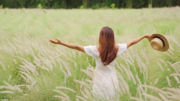 Young asian woman relaxing and enjoying in the flower field while traveling in summer