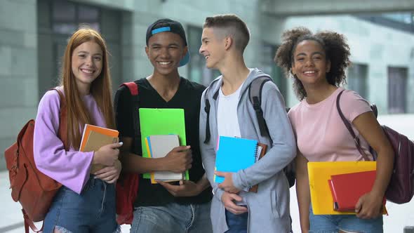 Multiracial High-School Students With Books Laughing and Smiling at Camera
