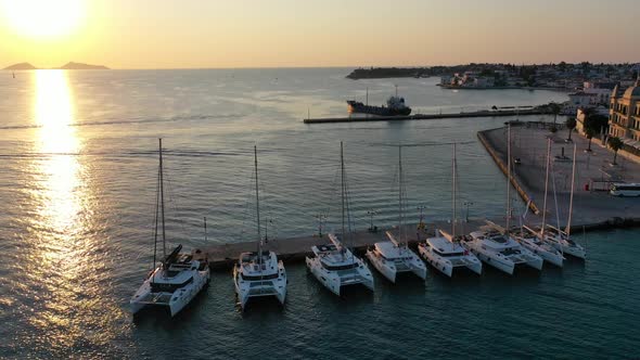 Catamaran and Sail Yachts Anchored at Bay on Deep Blue Sea Water on Sunrise