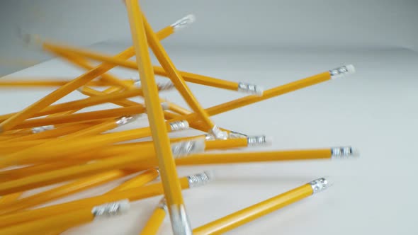 Yellow Pencils are Falling in Slow Motion on a White Table