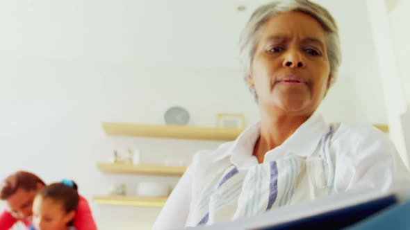 Grandmother reading recipe book in kitchen 4k