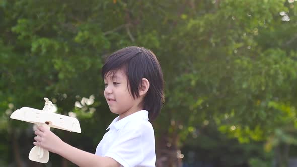 Cute Asian Child Playing Wooden Airplane In The Park Outdoors