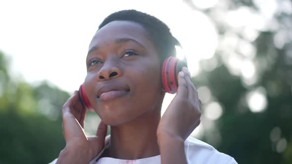 Closeup Slim Charming African American Woman in Headphones Smiling Listening to Music Standing in