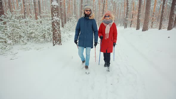 Couple Practicing Nordic Walking In Forest. Sticks Walking On Winter Wood. Winter Adventure Hiking.