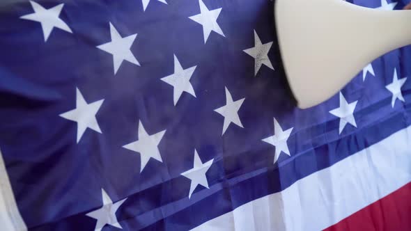 A Woman Strokes the US Flag with a Steam Iron. US Veteran Day Preparations