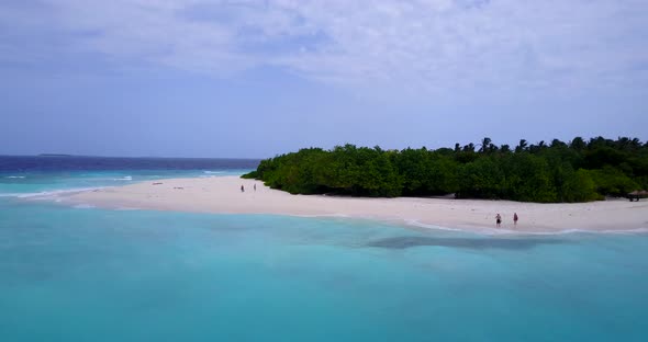 Wide birds eye travel shot of a white sandy paradise beach and turquoise sea background in vibrant 4