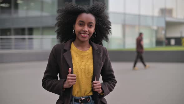 Young attractive black woman posing on city street background