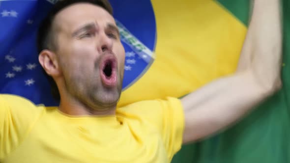 Brazilian Fan Celebrating While Holding the Flag of Brazil