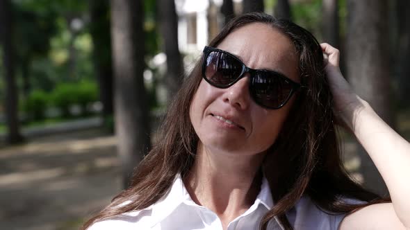 Portrait of Middleaged Brunette Woman with Black Sunglasses Outdoors at Summer Day