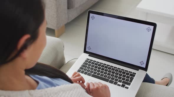 Back view of asian woman sitting on sofa, resting with laptop with copy space at home