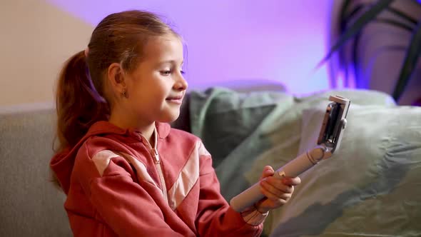 A little blonde girl calls her mother, grandmother or relatives via videoconference on a smartphone