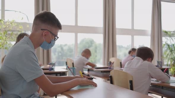 Multiracial Group of Kids Wearing Face Masks Working at Class Writing and Listening Explanations of