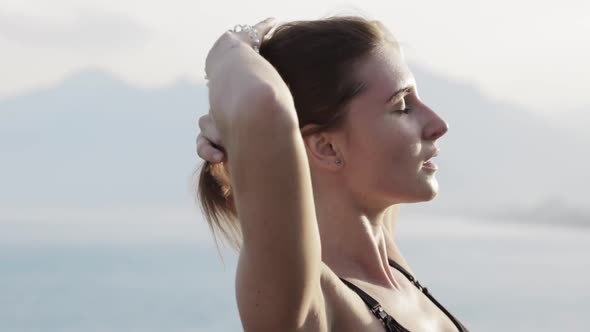 Fitness Woman Collects Her Hair in a Bun