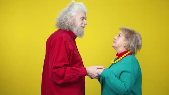 Side View of Happy Loving Senior Couple Dancing Slow Dance Holding Hands and Looking at Each Other