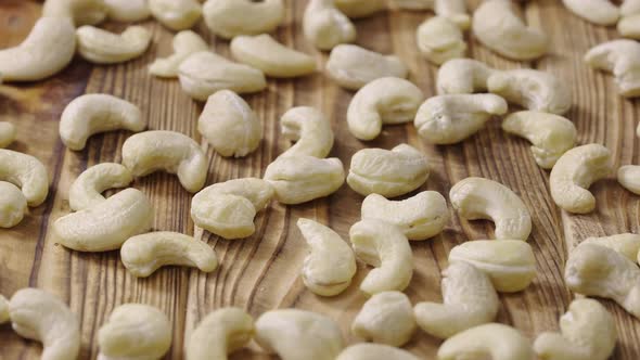 Sliding Shot of Fresh Raw Cashew Nuts Lying on a Textured Wooden Table Surface