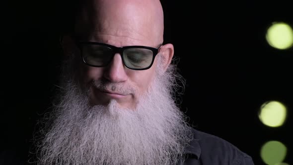 Close-Up Of Bald Man With Beard Using Mobile Phone Outdoors At Night