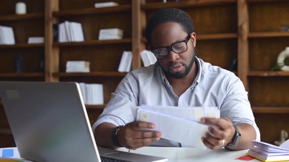 Young Business Man in Glasses Looking Through Correspondence