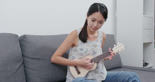 Woman play a song with ukulele at home