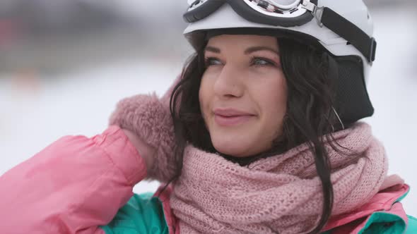 Closeup Portrait of Happy Young Charming Brunette Woman in Ski Helmet and Goggles Admiring Winter