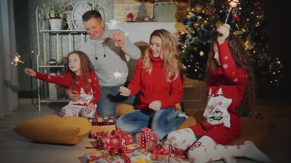 Cheerful Family of Four People with Sparklers Are Smiling and Looking To the Camera at the Foot of