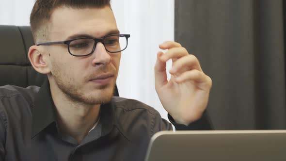 Portrait of Man Puts on Glasses and Looking at Laptop Screen