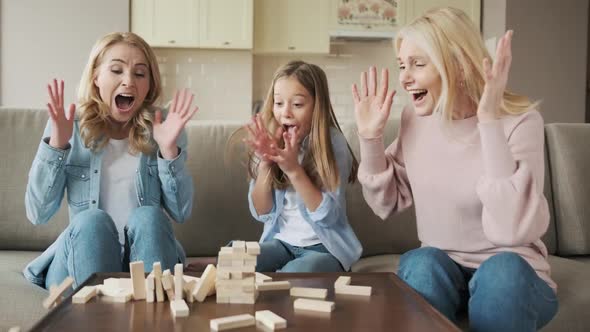 Three Generations Smiling Young Woman with Little Daughter and Mature Mother Building Wooden Tower