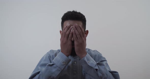 A Muslim raises his hands to his face while praying