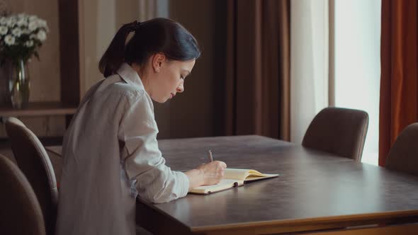 Attractive girl writing to notebook at home