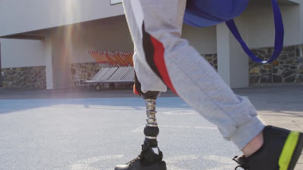 Back view of caucasian disabled male athlete with prosthetic leg walking