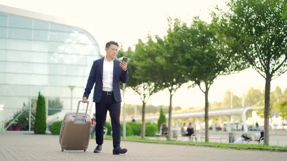 Asian tourist businessman walks with suitcase from terminal airport background a modern urban